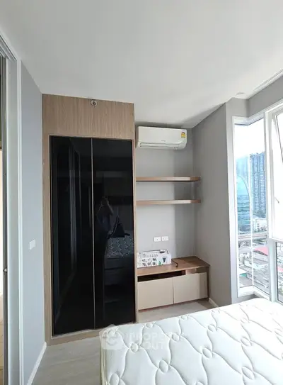 Modern bedroom with city view, featuring sleek wardrobe and air conditioning.