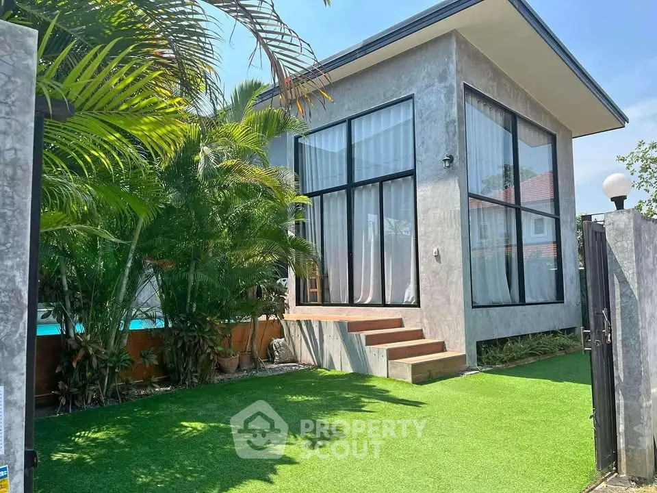 Modern house exterior with large windows and lush garden, perfect for serene living.
