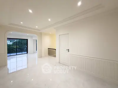 Spacious modern living room with elegant white interiors and large windows offering natural light and garden view.