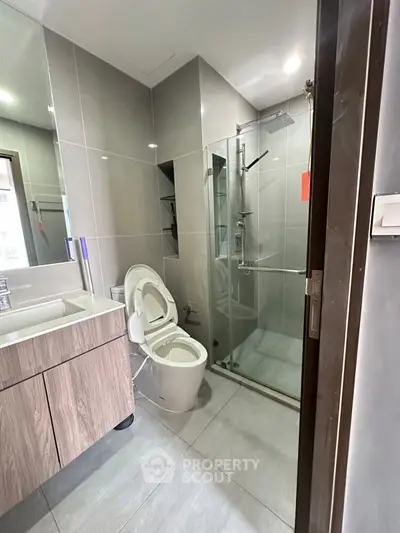 Modern bathroom with sleek design, featuring a glass shower enclosure and contemporary fixtures.