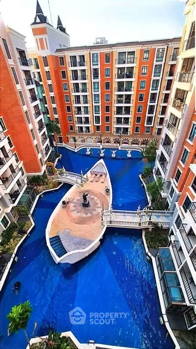 Stunning aerial view of luxury apartment complex with unique boat-shaped pool and elegant architecture.