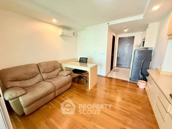 Modern living room with wooden flooring, cozy sofa, and study desk in a bright apartment.
