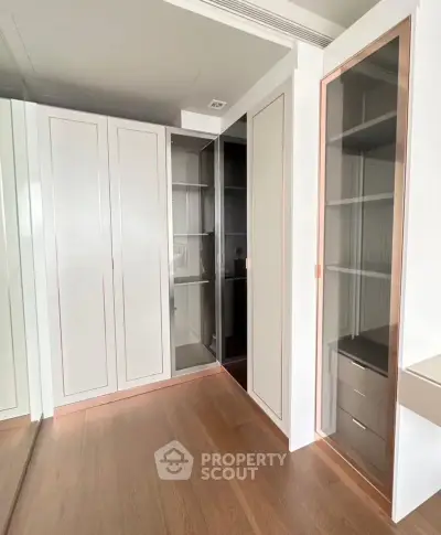 Spacious walk-in closet with elegant glass doors and ample storage space