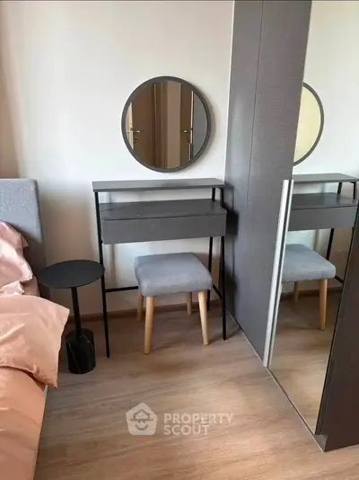 Modern bedroom corner with stylish vanity, mirror, and cozy stool in elegant apartment.