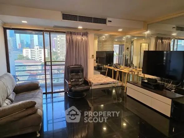 Spacious living room with city view, modern furniture, and large TV setup.