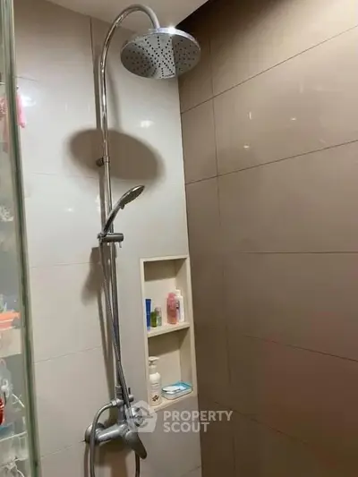 Modern bathroom with sleek showerhead and built-in shelving for toiletries.