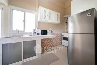 Modern kitchen with stainless steel fridge and sleek countertops in a stylish apartment.