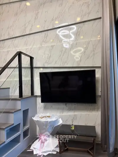 Modern living room with stylish staircase and wall-mounted TV, featuring elegant decor and contemporary design.