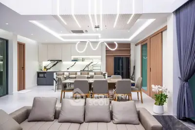 Luxurious open-plan living room with modern kitchen and elegant dining area, featuring stylish lighting and contemporary decor.
