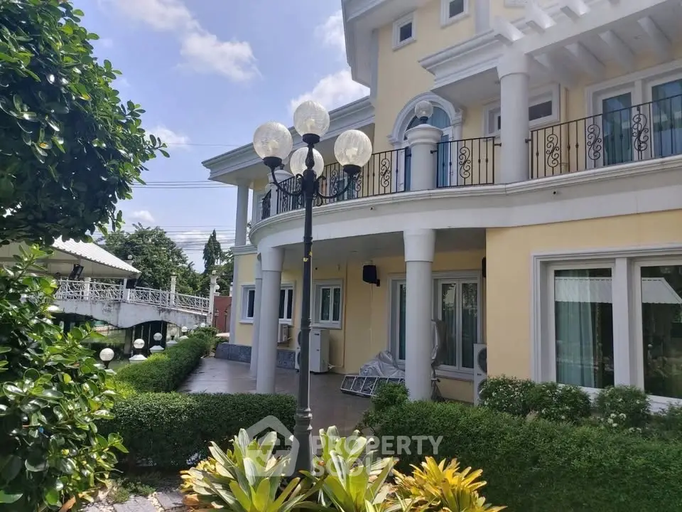 Elegant two-story house with balcony and lush garden, perfect for luxurious living.