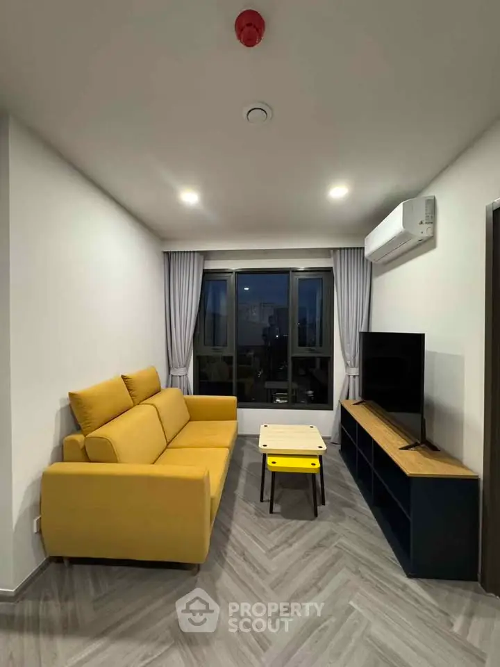 Modern living room with yellow sofa, sleek TV unit, and large windows.
