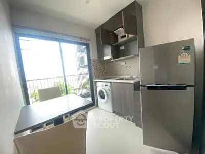 Modern kitchen with washing machine and balcony view in compact apartment.