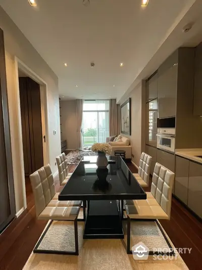 Modern dining area with sleek black table and elegant white chairs in a stylish apartment.