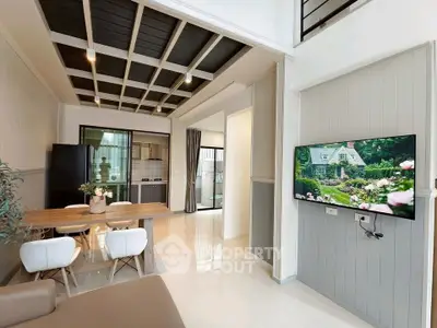Modern open-plan living room with stylish kitchen and dining area, featuring sleek furniture and elegant decor.