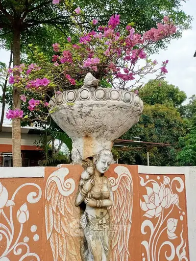 Charming garden with ornate statue and vibrant flowers, perfect for serene outdoor living.