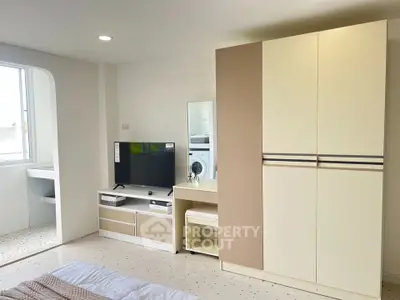 Modern bedroom with sleek wardrobe and entertainment unit, featuring a minimalist design and ample natural light.