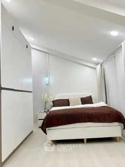 Modern bedroom with sleek white wardrobe and cozy bed in stylish apartment.