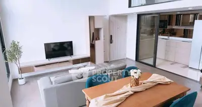 Modern open-plan living room with dining area and sleek kitchen, featuring stylish decor and natural light.