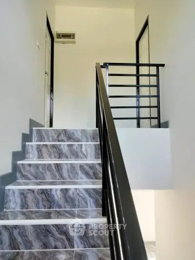 Modern staircase with elegant marble tiles and sleek railing in a contemporary home.