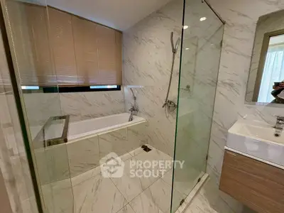 Luxurious bathroom with marble tiles, glass shower, and modern fixtures
