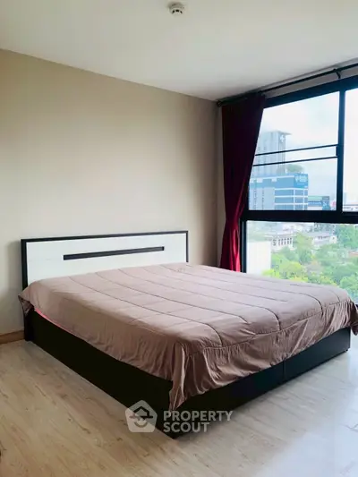 Spacious bedroom with large window offering city views in modern apartment.