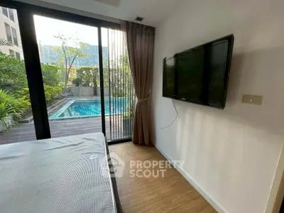 Modern bedroom with pool view and wall-mounted TV, featuring floor-to-ceiling windows.