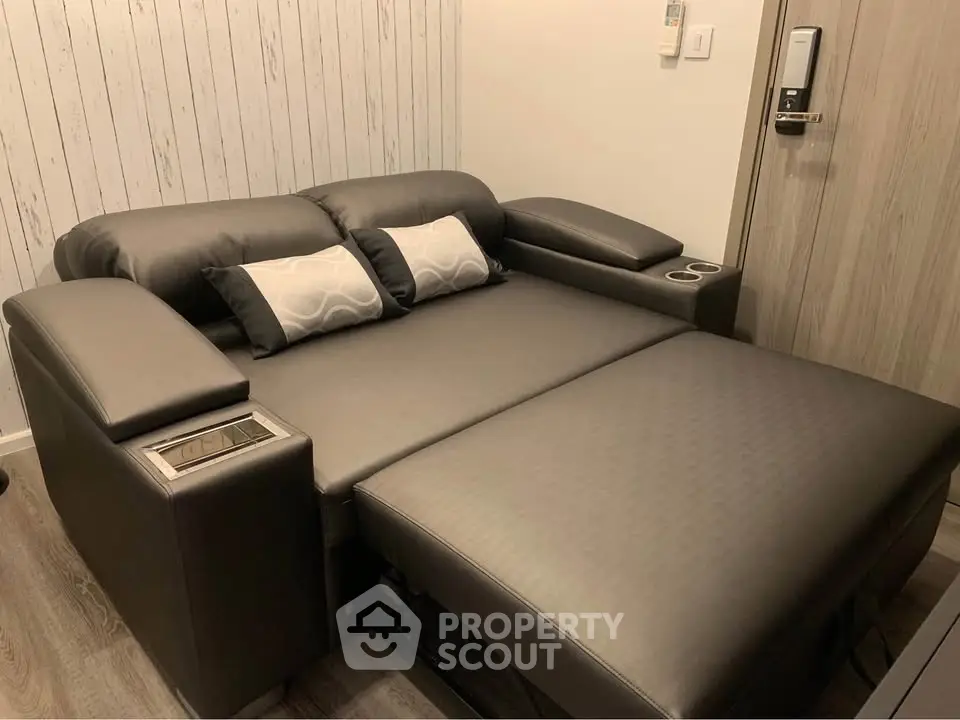 Modern living room with sleek black leather sofa bed and stylish decor.