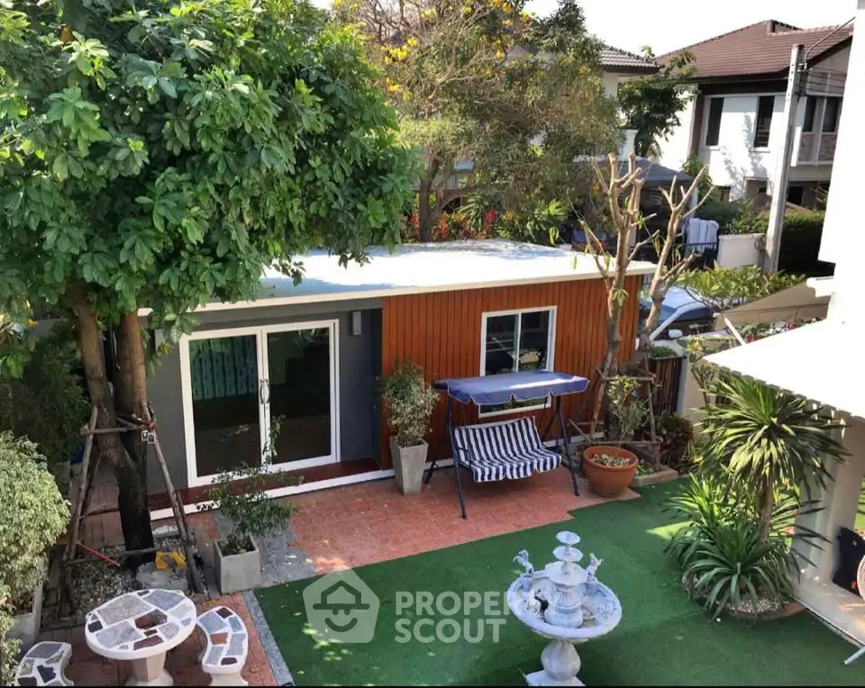 Charming backyard with lush garden and cozy seating area, perfect for relaxation.