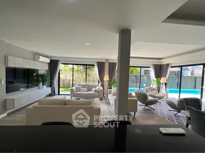 Luxurious open-plan living room with pool view, modern furniture, and abundant natural light.