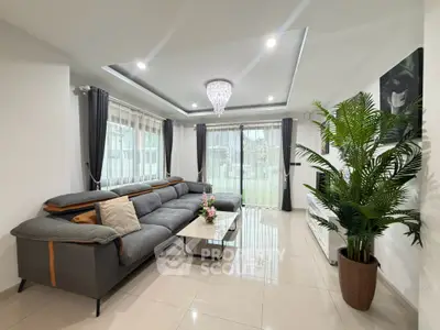 Spacious modern living room with elegant chandelier and large windows offering natural light.