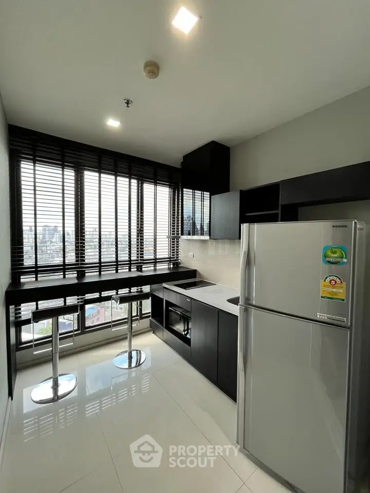 Modern kitchen with sleek black cabinetry and stainless steel appliances, offering a stunning city view.