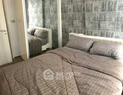 Cozy bedroom with stylish gray bedding and mirrored wardrobe in modern apartment.