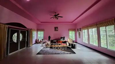 Spacious living room with pink walls, large windows, and cozy seating area.