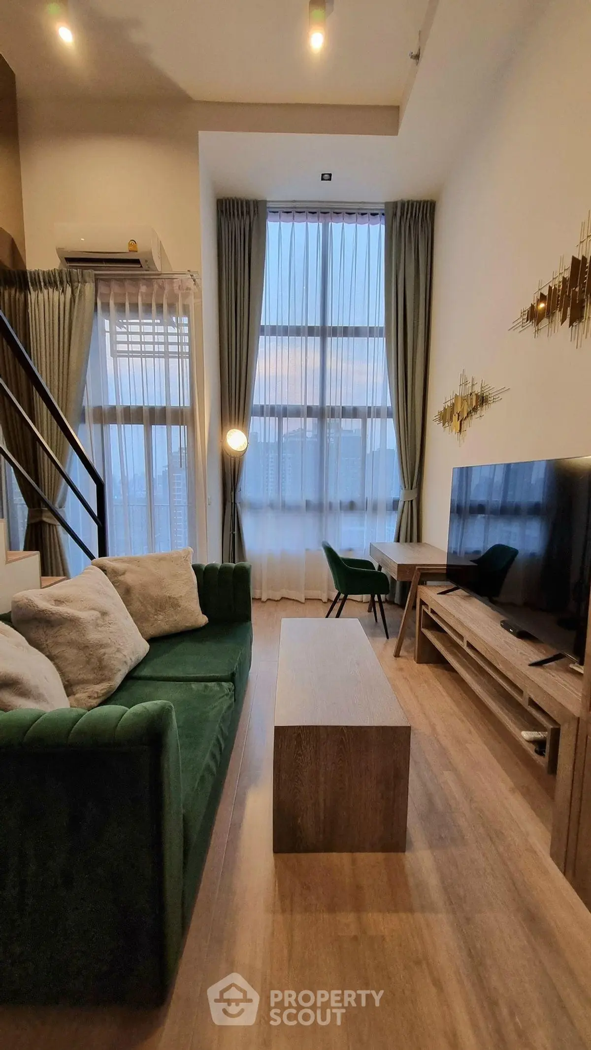 Modern living room with high ceilings, stylish green sofa, and elegant decor in a contemporary apartment.