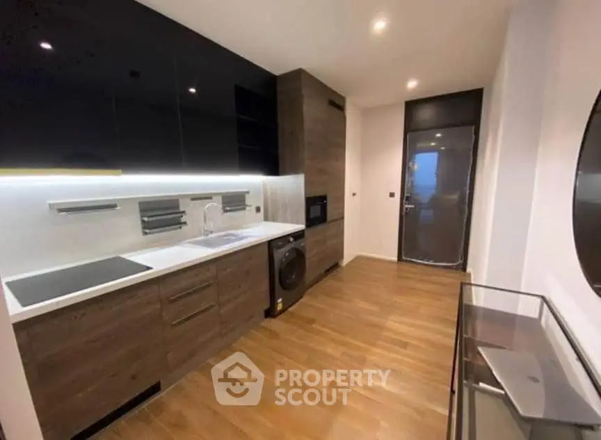 Modern kitchen with sleek cabinetry, built-in appliances, and wooden flooring in a stylish apartment.