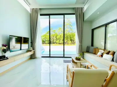 Spacious living room with pool view, modern decor, and large windows for natural light.