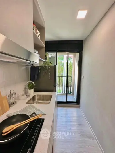 Modern kitchen with sleek design and balcony view, featuring induction cooktop and stylish cabinetry.