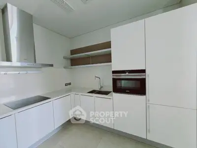 Modern minimalist kitchen with sleek white cabinetry and built-in appliances.