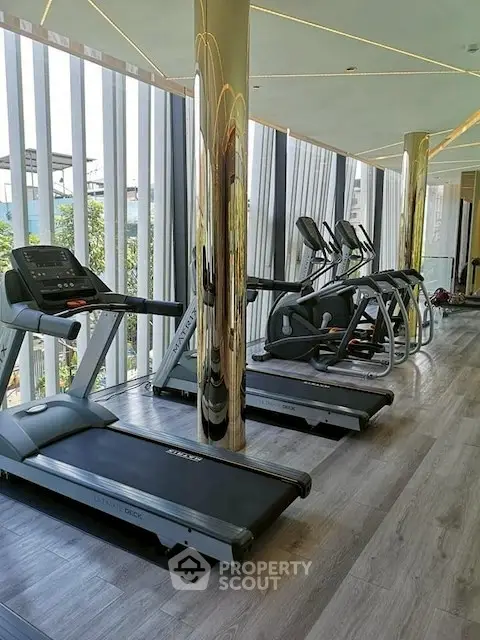 Modern gym with treadmills and elliptical machines in a luxury residential building.
