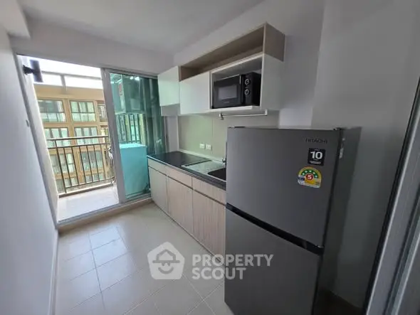Modern kitchen with balcony view, featuring sleek appliances and ample storage in a compact layout.