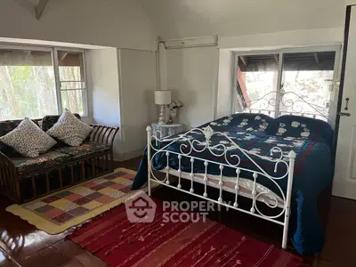Charming bedroom with vintage metal bed and cozy seating area in rustic home.