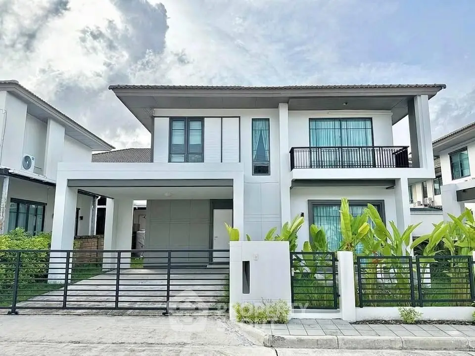 Modern two-story house with sleek design and lush greenery in a suburban neighborhood.