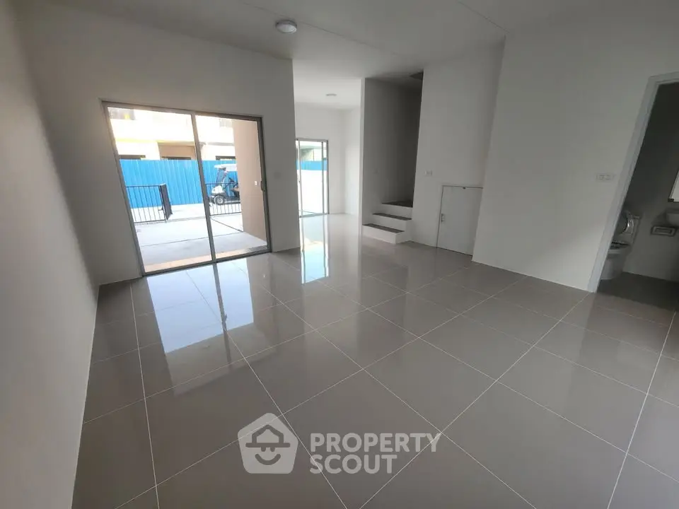 Spacious modern living room with glossy tiled floors and sliding glass doors