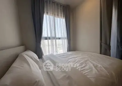 Cozy bedroom with large window and elegant curtains, offering natural light and a serene atmosphere.
