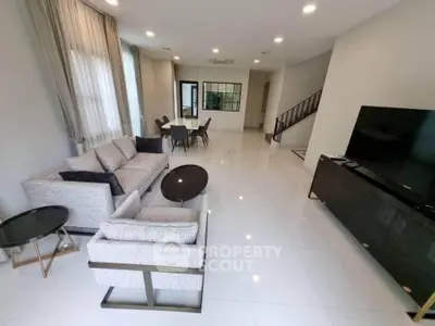 Spacious modern living room with elegant furniture and large TV, perfect for family gatherings.