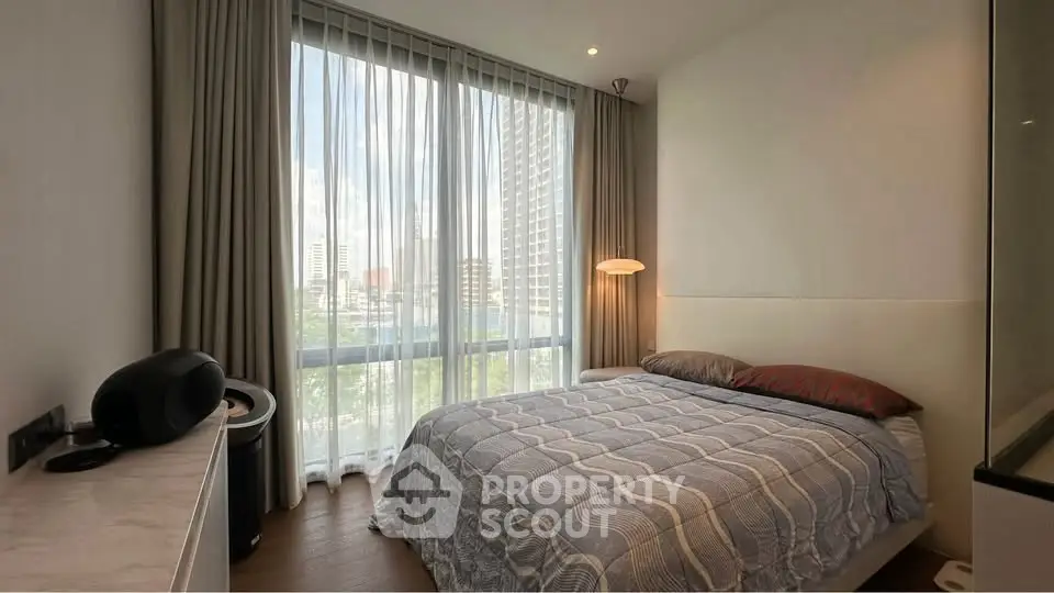 Modern bedroom with large window and city view, featuring stylish decor and natural light.