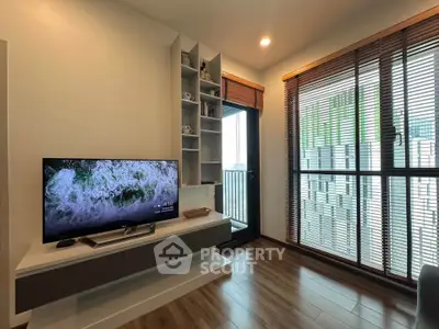 Modern living room with sleek TV setup and large windows offering natural light.