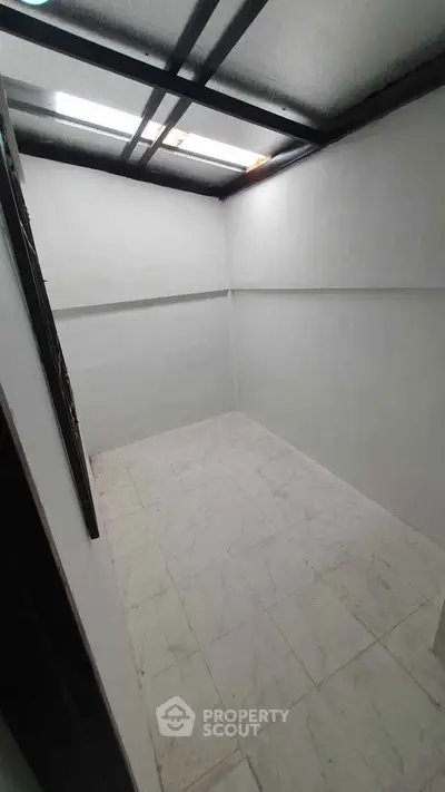 Spacious white-tiled storage room with natural light from ceiling windows.