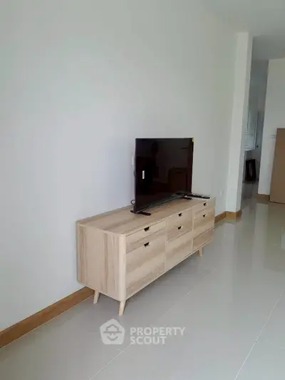 Modern living room with sleek TV stand and flat-screen TV, showcasing minimalist design and bright tiled flooring.