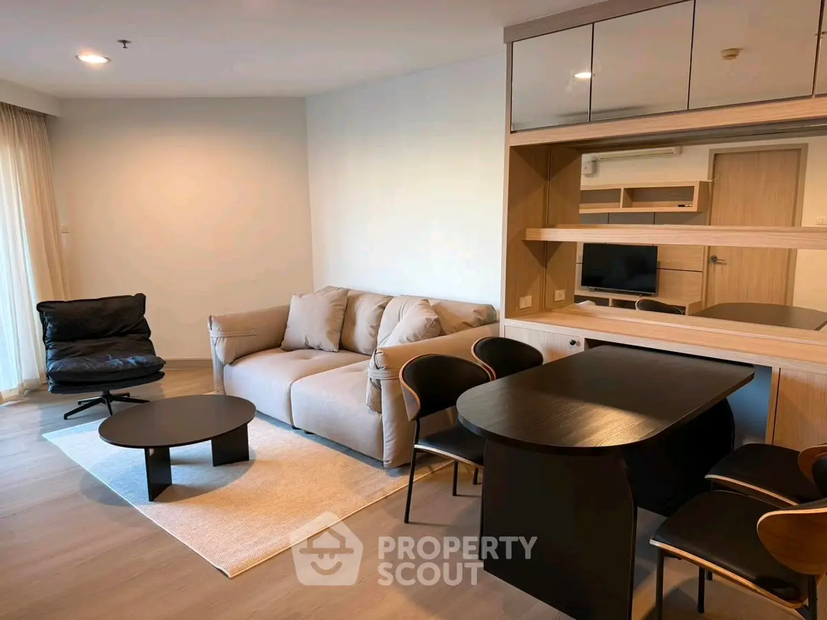Modern living room with cozy sofa, stylish chairs, and sleek table in a well-lit apartment.